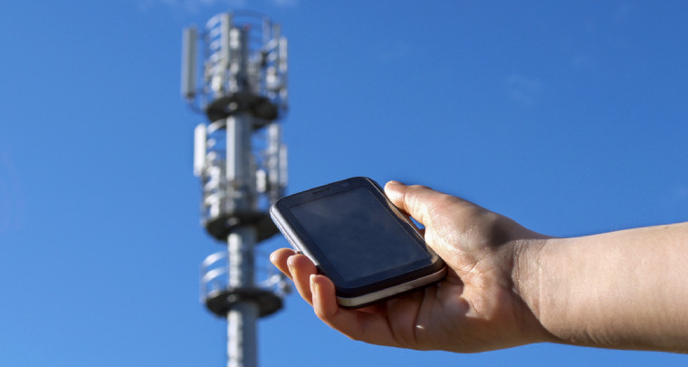 Hand holding a smartphone nearby a cellular radio