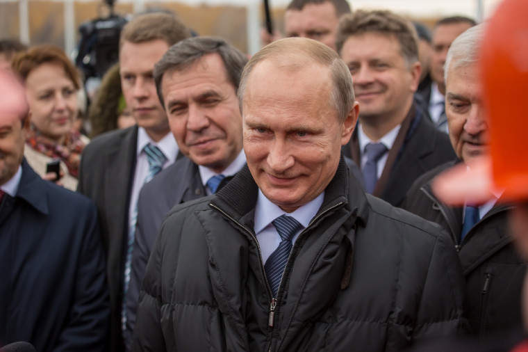 Putin smiling with some officials behind him