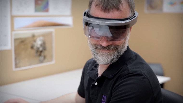 A man smiling with a HoloLens on his head