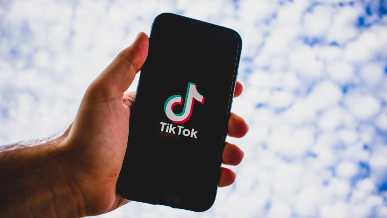 A man holding a phone with the TikTok logo displayed