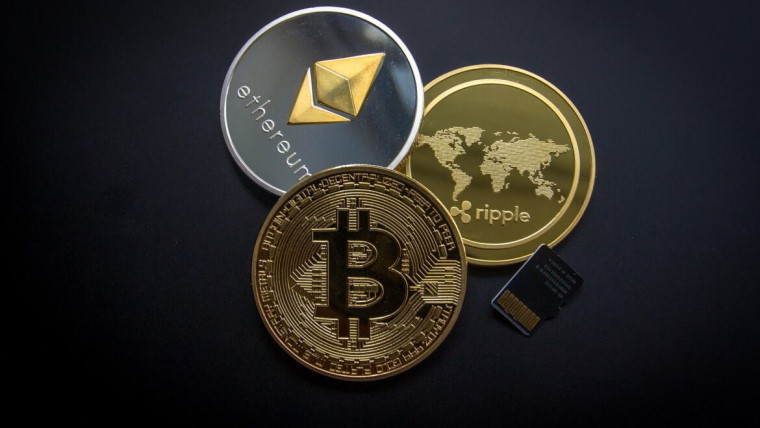 Bitcoin, Ethereum and Ripple coins and SD card on grey background