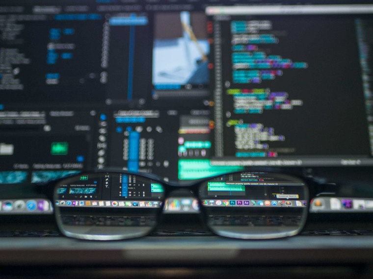 A laptop display with a coding IDE open and spectacles in the front