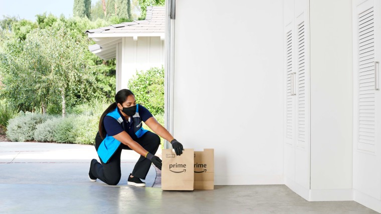 An Amazon shopping specialist leaves a grocery package at a garage