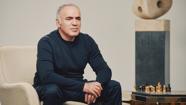 Garry Kasparov sitting next to a chess board