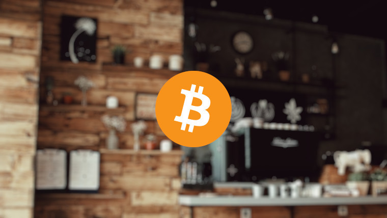 The Bitcoin logo in front of a coffee shop interior