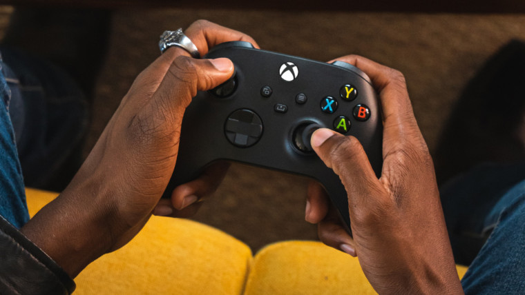 A man holding a black Xbox wireless controller.