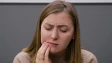 a lady holding her cheek indicating tooth ache