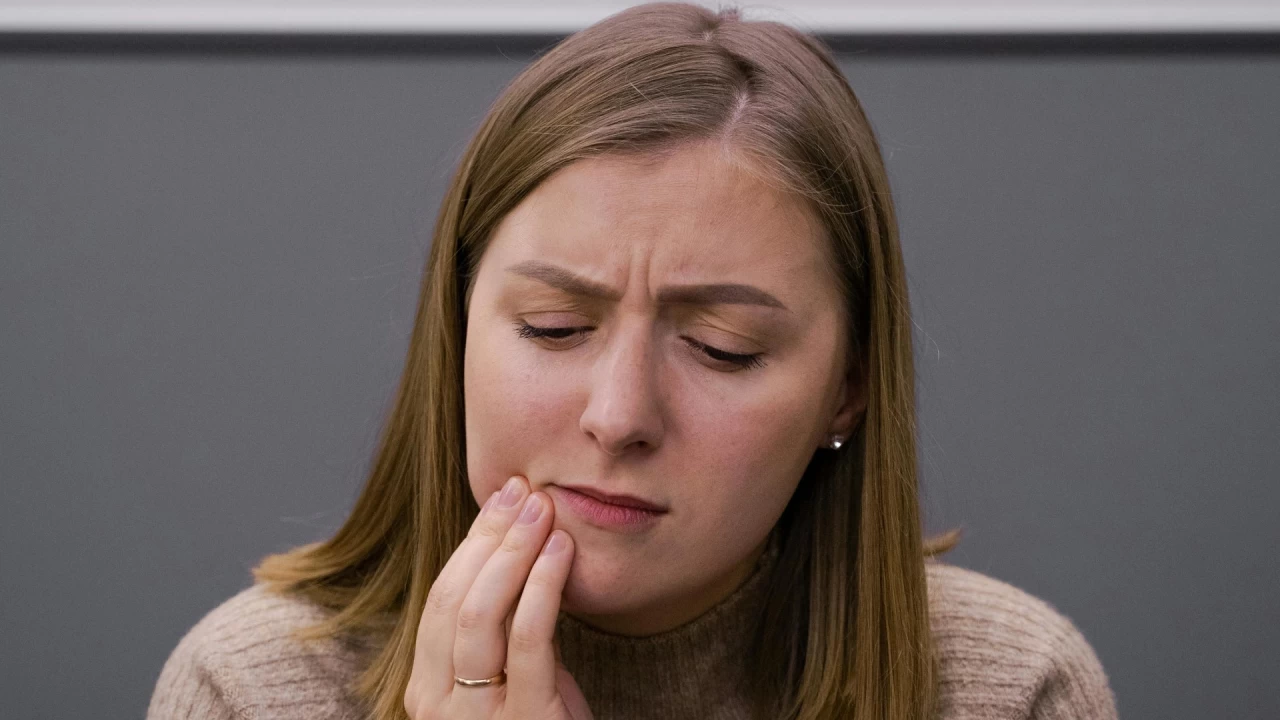 a lady holding her cheek indicating tooth ache
