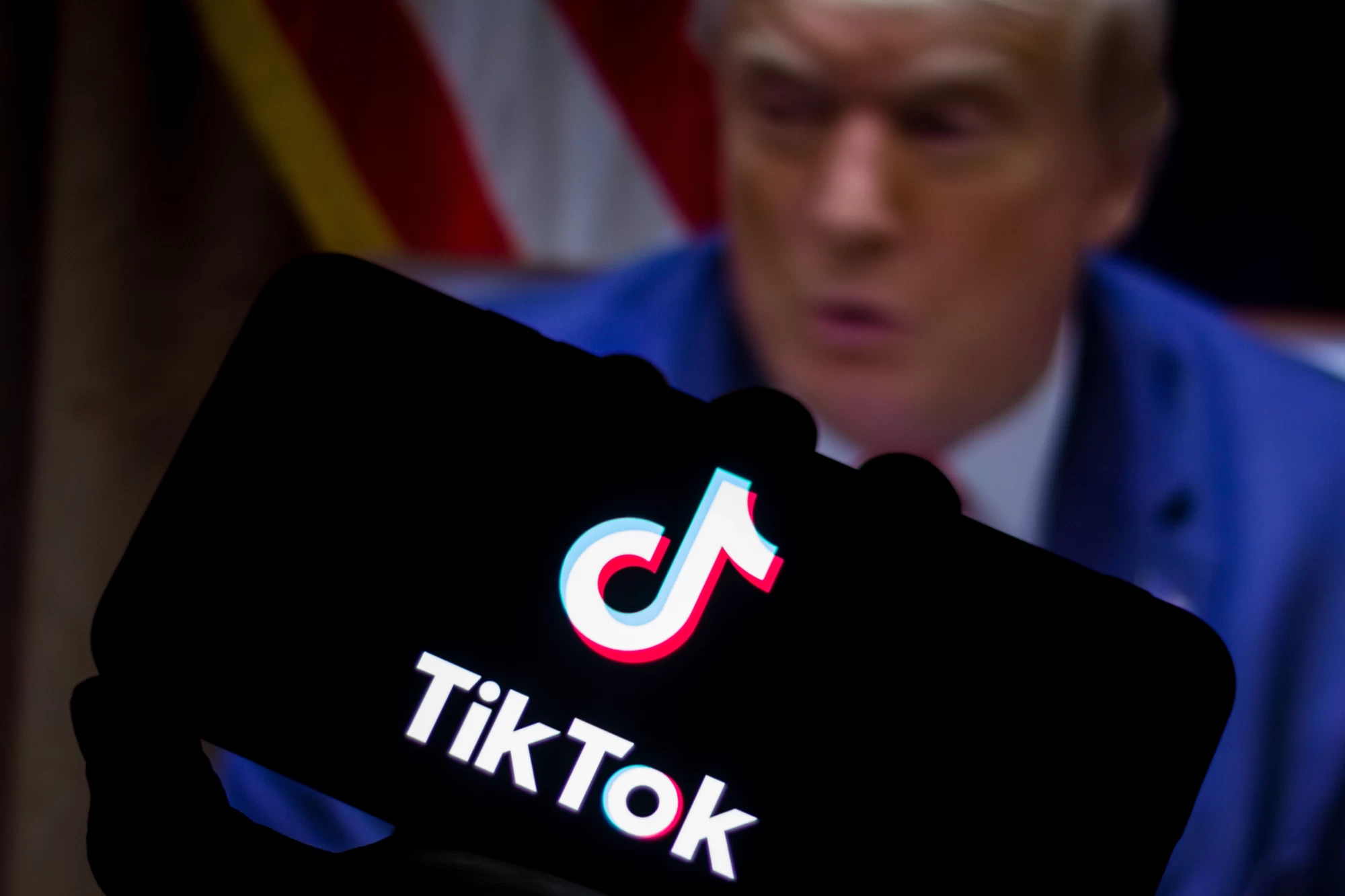 TikTok logo seen displayed on a smartphone United States President Donald Trump appears in the backg