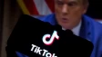 TikTok logo seen displayed on a smartphone United States President Donald Trump appears in the backg
