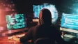 A hacker looking at multiple screens rear view