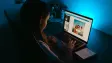 Child sitting at a computer in a dark room